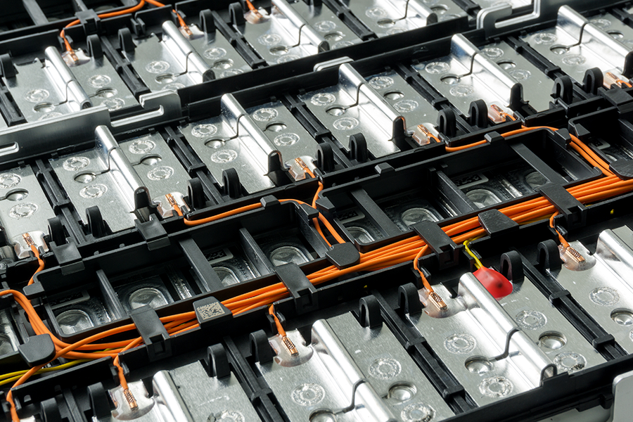 A detailed view of the inner components of a lithium-ion battery pack, showing silver cells, black casing, and orange wires.