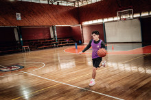 Jugador de básquetbol boteando balón en gimnasio  