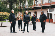 5 integrantes del grupo musical posan de pie en el patio de la Escuela de Artes y Oficios