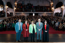 5 personas en el escenario del Aula Magna y de fondo el público de pie posando para la cámara