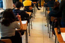 Estudiantes sentados en pupitres de una sala de clases  