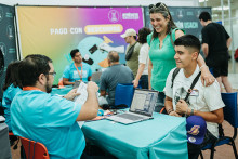 Mujer sonríe junto a estudiante en feria de postulantes