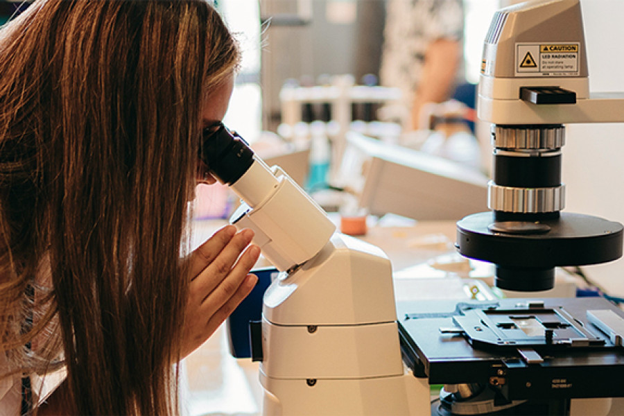 Mujer mira a través del microscopio 