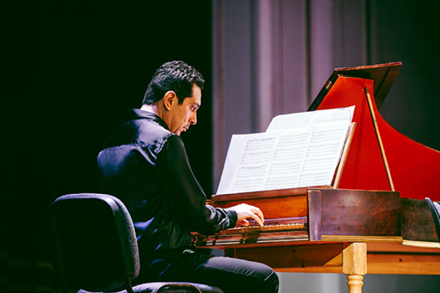 Maestro toca el piano. De fondo, un telón negro.