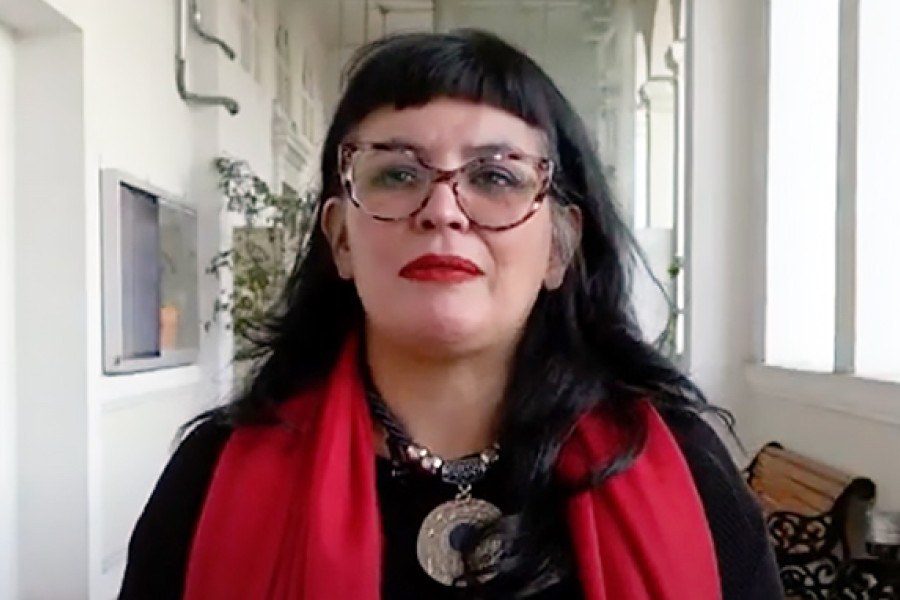 Académica Claudia Calquín, posando a la cámara en el edificio de la Escuela de Periodismo y Psicología Usach