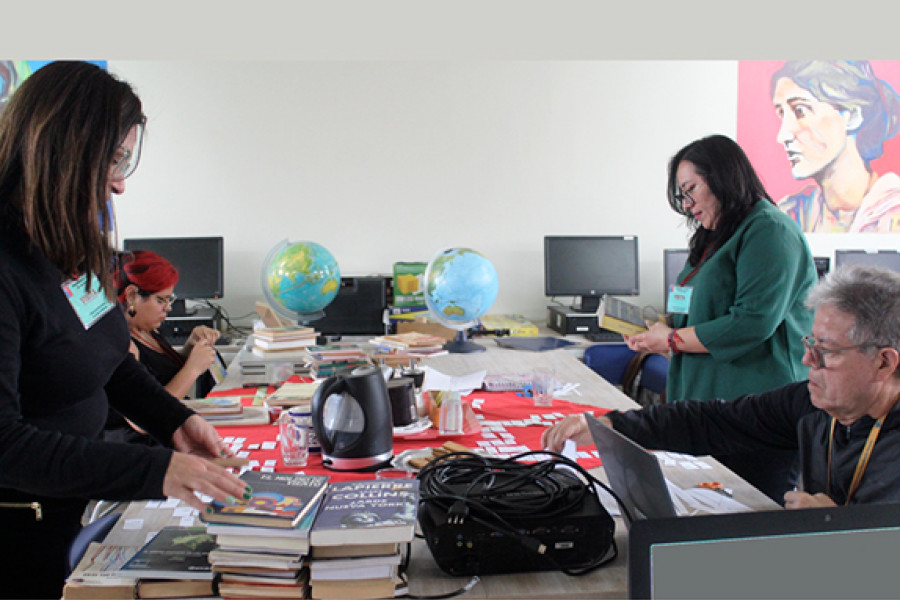 Bibliotecarias y estudiantes en biblioteca CRA de escuela en Centro Penitenciario Femenino de San Miguel. Mesas de trabajo y materiales bibliográficos.