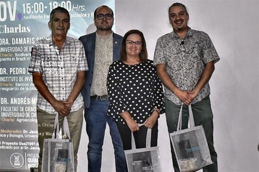 Investigadores posan a la cámara en escenario auditorio de la Facultad de Química y Biología