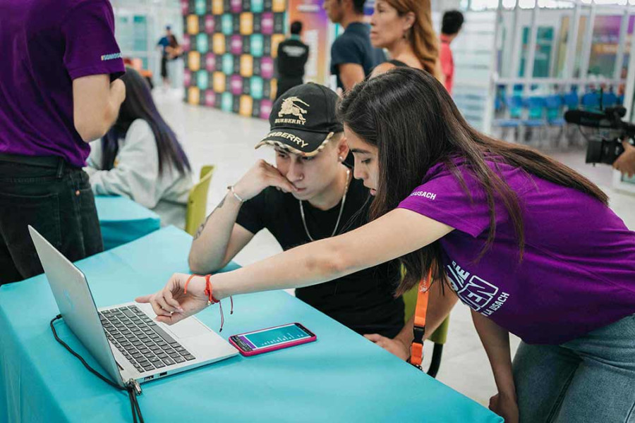 Asistente de admisión apoya a joven en su proceso de matricula en un notebook