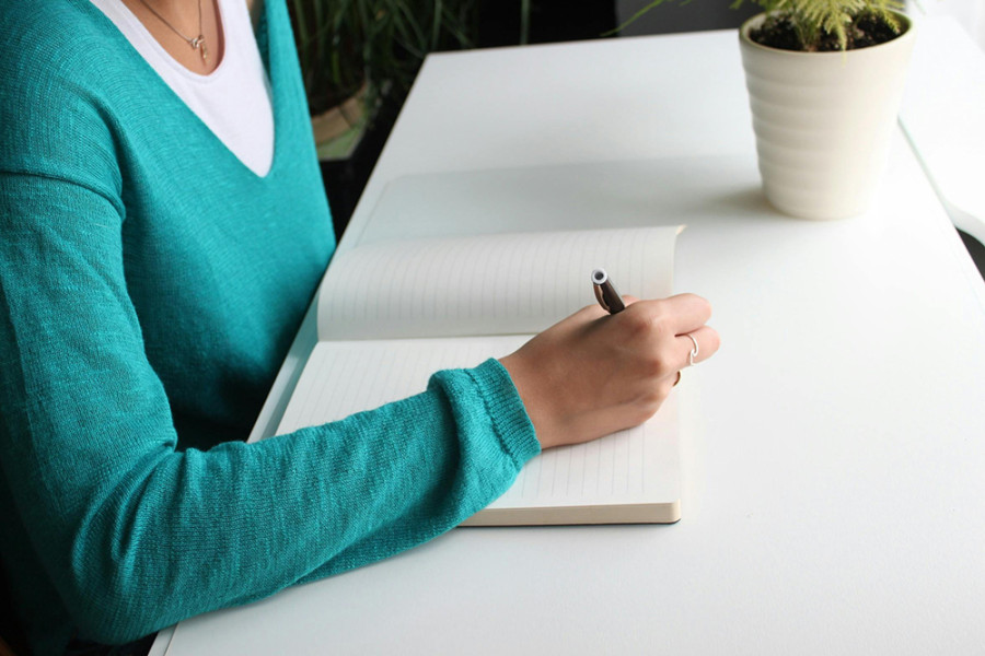 Imagen de estudiante escribiendo sobre un cuaderno. 