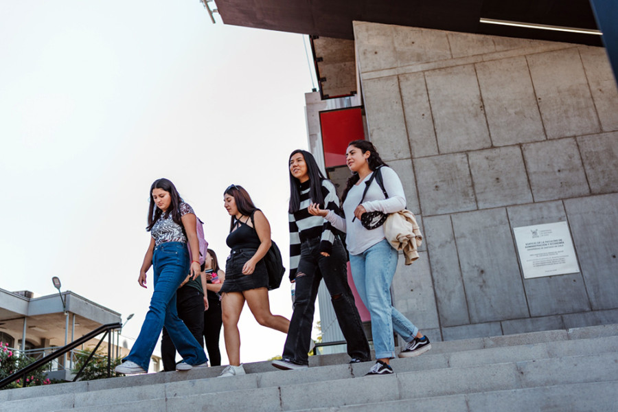 Estudiantes mujeres bajan por escalera de entrada principal de la Facultad de Administración y Economía (FAE)