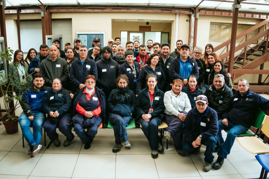 En la imagen aparecen funcionarios de aseos y jardines la universidad posando a la cámara. Son aproximadamente 40 personas que en su mayoría llevan puesto un polerón corporativo azul 