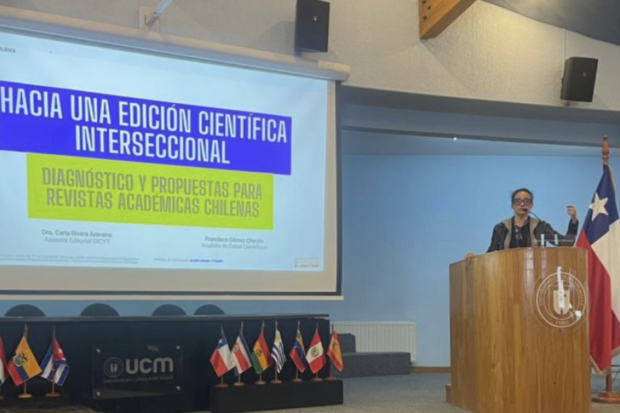 Mujer en el podio realiza presentación proyectada en una pantalla