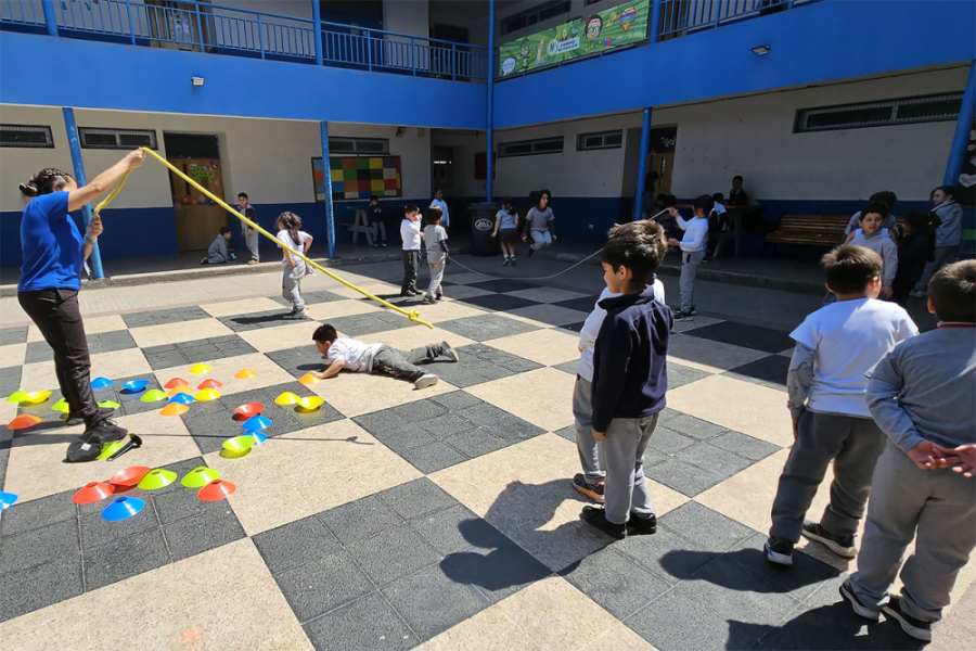 Estudiantes de enseñanza básica realizan ejercicios en el patio de un establecimiento escolar.