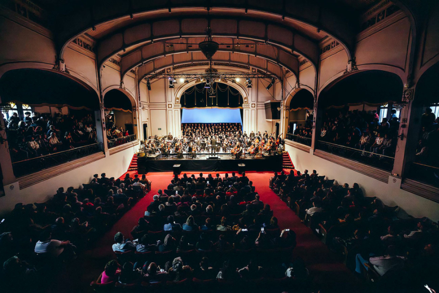 En la imagen aparece una toma general del Teatro Aula Magna, en toda su capacidad, y con la Orquesta Usach en el escenario principal