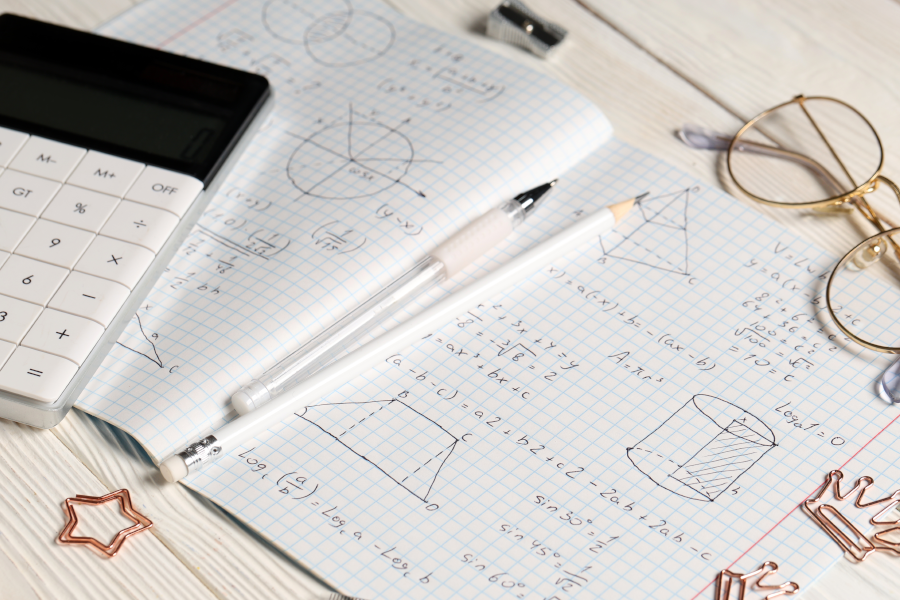 A notebook with geometric sketches, a calculator, and glasses.