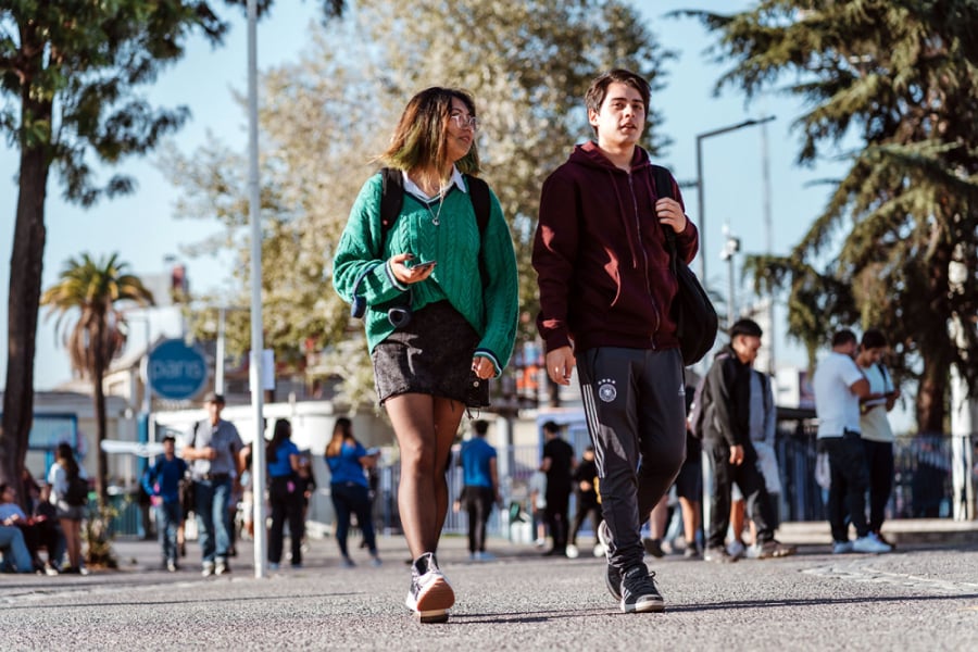 La imagen muestra dos estudiantes caminando por el campus 