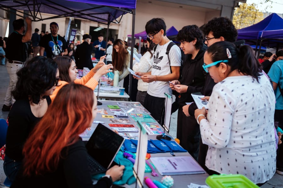 En la imagen aparecen tres mujeres de un stand de la feria enseñando sus temáticas a tres hombres y una mujer