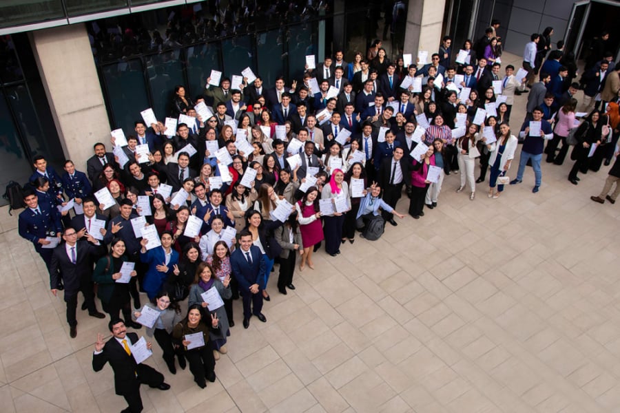 En la imagen aparecen alrededor de 30 estudiantes premiados por el Colegio de Ingenieros de Chile. La imagen es un picado desde altura y los estudiantes miran hacia arriba.
