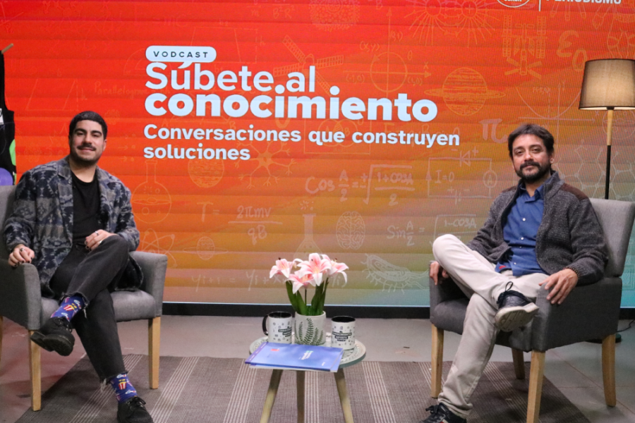 En la imagen aparece el set de grabación del posdcast junto al conductor y su entrevistado. Fondo naranjo y rodo, letras blancas.