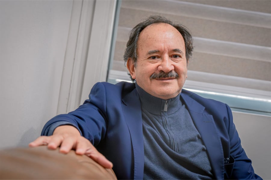 En la imagen aparece el Dr. Abello con una chaqueta azul sentado sobre un sillón en su oficina-