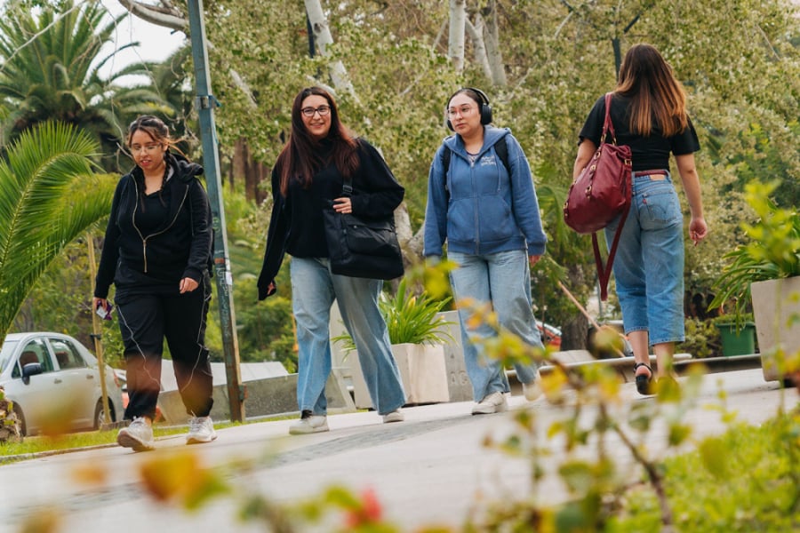 En la imagen aparecen 4 estudiantes de nuestra universidad caminando por el sector de arquitectura y periodismo