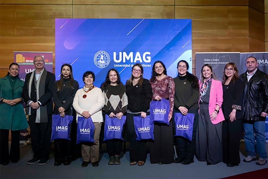 La imagen muestra a las y los asistentes al evento, con una bolsa azul de la Universidad de Magallanes en sus manos, en el lugar del evento