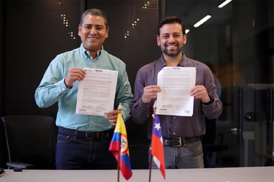 En la imagen aparece académico Factec y académico de una universidad colombiana enseñando la firma del acuerdo.