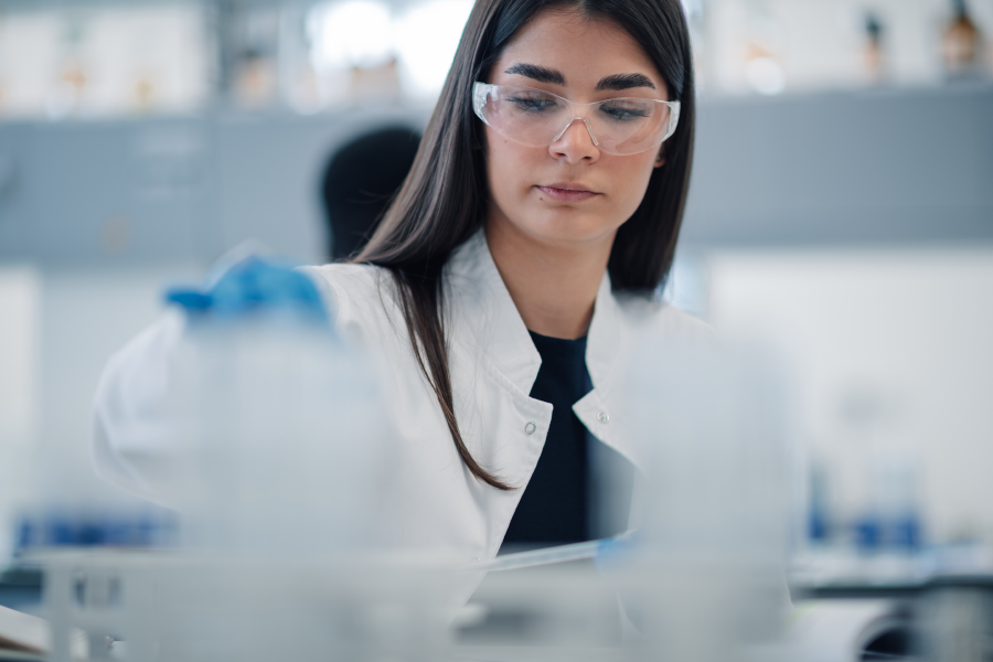 Female scientist wearing safety glasses working in a laboratory setting.