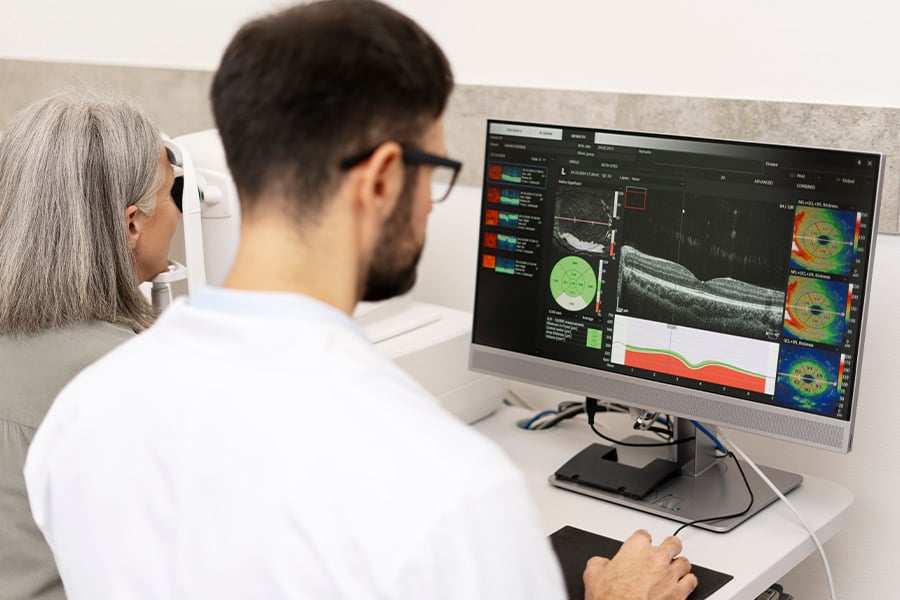 Doctor analyzing ocular scan results on monitor while examining patient.