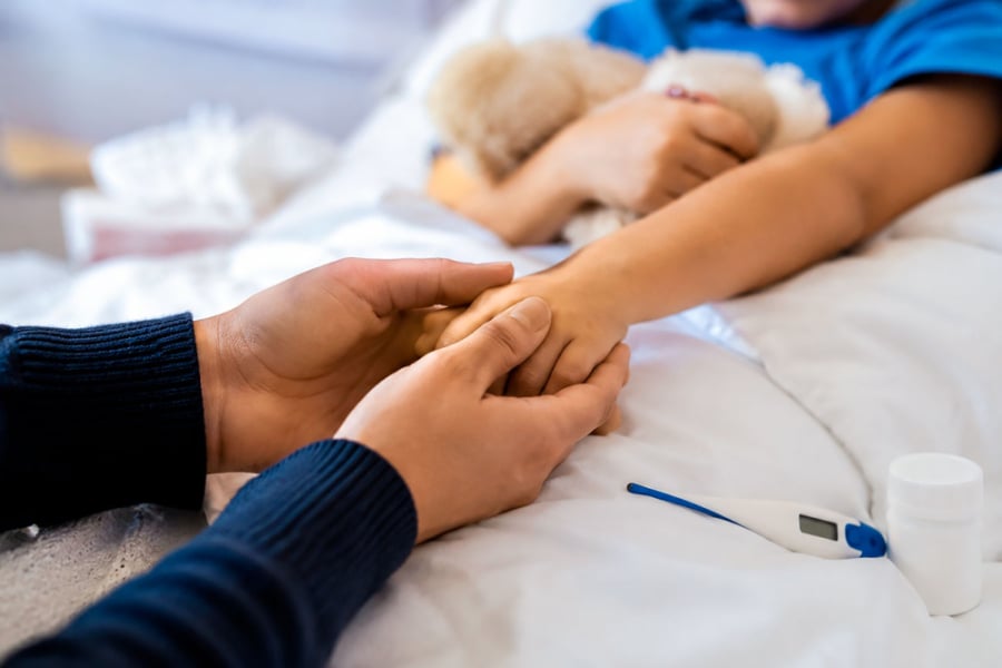 La imagen corresponde al cuidado de una persona a otra en un hospital, pero solo se enfoca en las manos que corresponde a un adulto y un niño.