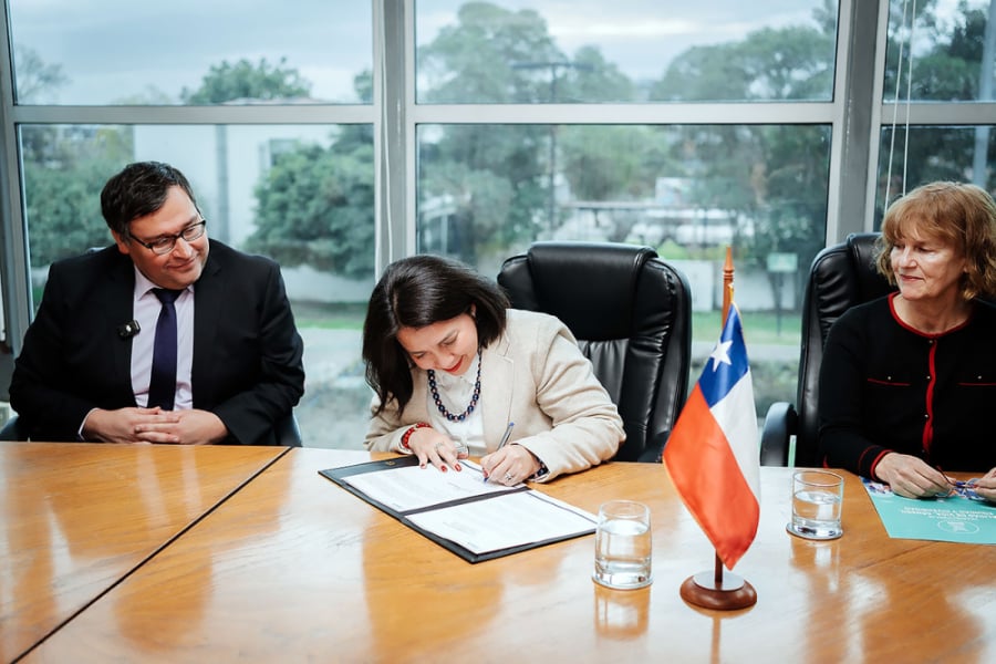 La imagen muestra a la vicerrectora firmando el documento en la sala de reuniones de rectoría. A su lado están otras autoridades que participaron de la firma