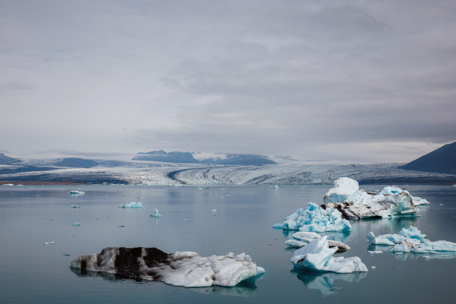 Icebergs flotando en aguas tranquilas frente a un glaciar ártico que se derrite.