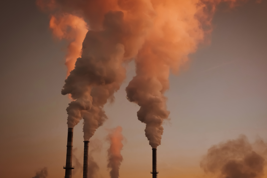 Chimeneas industriales que emiten densas columnas de humo al atardecer.