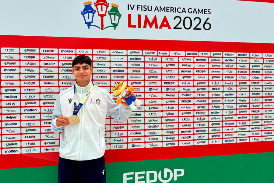 En la fotografía aparece Víctor Jara, estudiante Usach quien logró una destacada actuación en FISU América Games 2026.. Aparece con una chaqueta de buzo blanca, una de sus medallas y la mascota del evento. De fondo, un panel con los sponsor del evento.