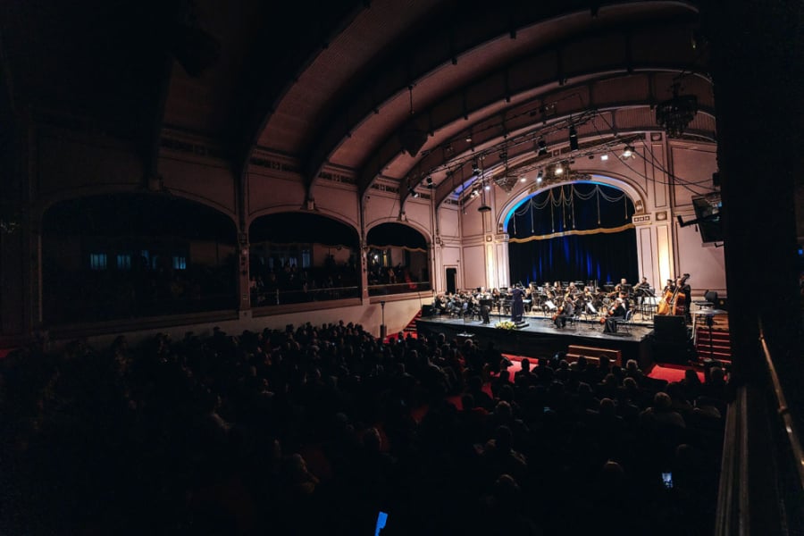 La foto muestra el Aula Magna con la orquesta usach tocando en el escenario