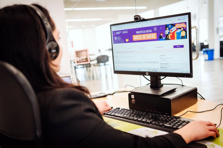 En la imagen aparece una estudiante con audífonos frente la monitor de la computadora entrando al servicio digital