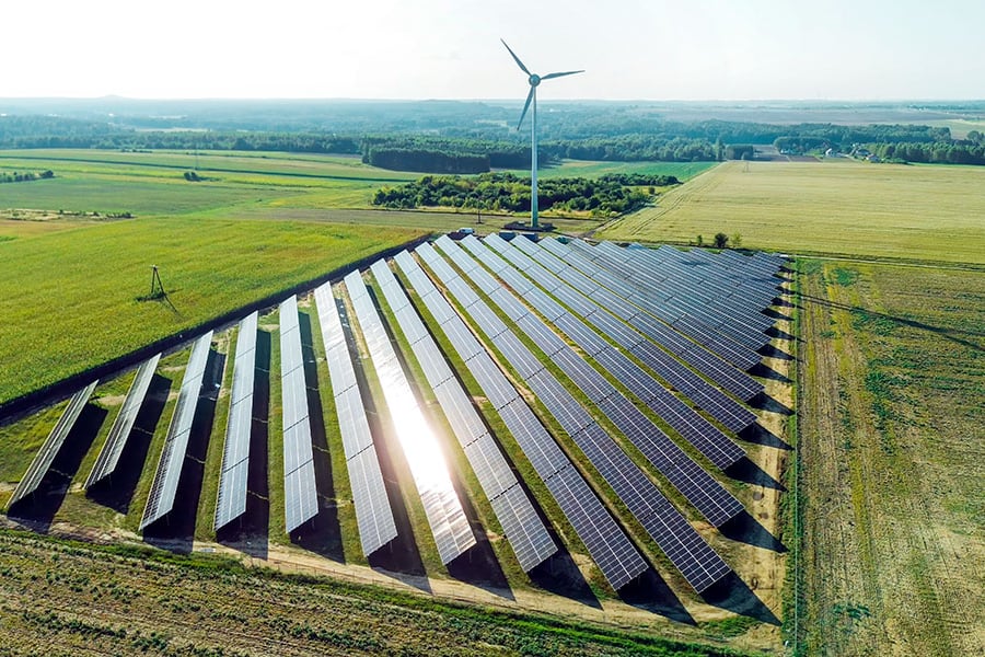 Un gran conjunto de paneles solares junto a una turbina eólica.