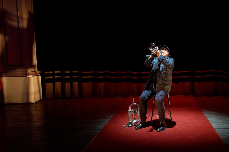 En la imagen aparece el músico de la Orquesta Usach tocando su trompeta en el escenario central del Teatro Aula Magna
